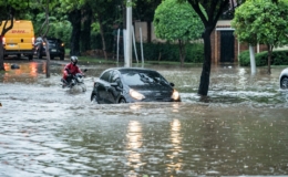 Ilustrasi mobil melintasi jalan tergenang banjir saat hujan deras